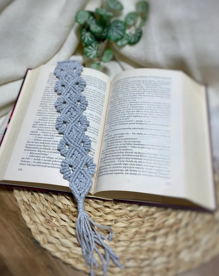 Open book with blue knitted bookmark placed on woven circular surface with potted plant in background
